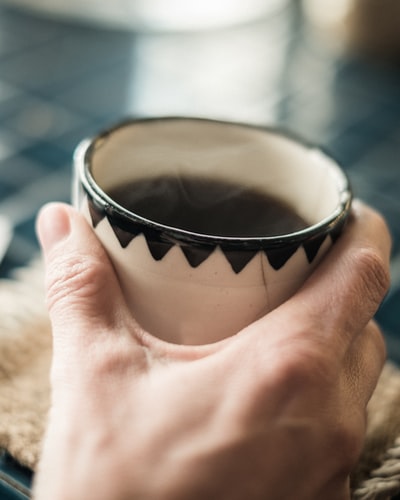 手持白色陶瓷茶杯的人